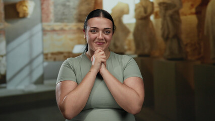Woman smiling and clapping in modern museum with sculptures and soft lighting, showcasing joy and...