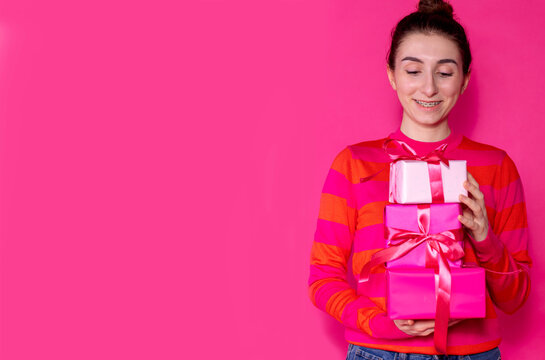 Half of the girl in a pink sweater with gifts on a pink background - Powered by Adobe