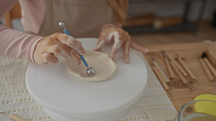 Woman shapes smooth small clay bowl with hands in pottery studio; craftsmanship focus creativity...