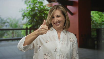 Woman in white shirt points finger at building in resort courtyard smiling warmly in daylight;...