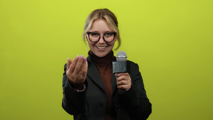 Reporter woman with glasses holding microphone gestures invitingly against vibrant blue background...