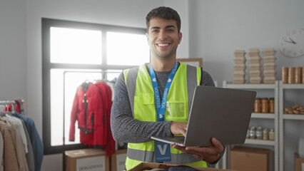 Man uses laptop while typing at center alongside young hispanic volunteer handling donations with...