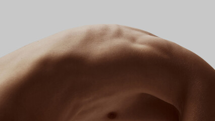 Bare male back with visible muscle curve and bent posture on neutral background. Concept of body...