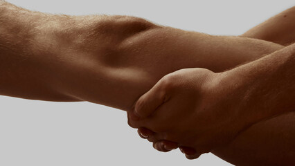 Male hands gently gripping under knee in isolated gesture on grey background. Concept of modern...
