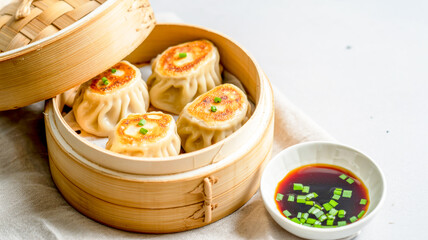 A high-quality food photograph of four golden-brown pan-fried dumplings arranged in a bamboo steamer basket