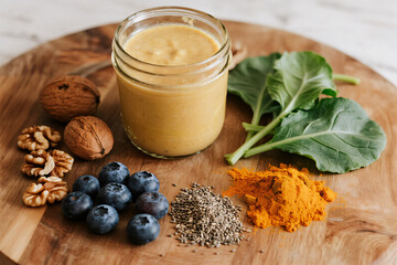 Top view of natural brain-boosting smoothie ingredients on rustic table: blueberries, turmeric, walnuts, chia seeds, spinach, in blender jar, soft light, cinematic aesthetic
