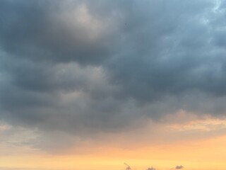 Dramatic sky at sunset with beautiful orange, blue, and grey clouds. A perfect natural background