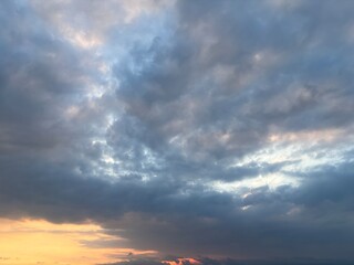 Dramatic sky at sunset with beautiful orange, blue, and grey clouds. A perfect natural background