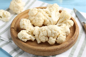 Pieces of cauliflower and knife on light blue wooden table, closeup