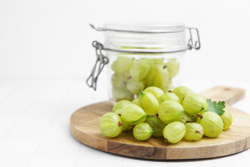 Fresh green gooseberries on white tiled table, closeup