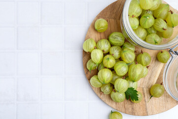 Fresh green gooseberries on white tiled table, top view. Space for text