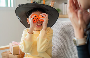 Halloween Fun. A young boy wearing a witch hat, playfully holding Halloween decorations.