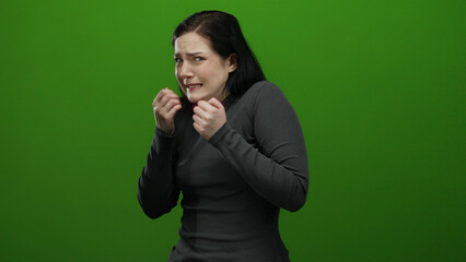 Woman expressing nervousness in green background setting, her emotions captured in vivid detail...