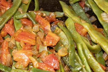 Fried green beans with tomato and onion pieces. Tasty meal with french bean on dinner or lunch on the pan