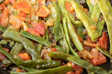 Fried green beans with tomato and onion pieces. Tasty meal with french bean on dinner or lunch on the pan
