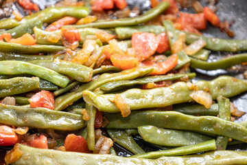 Fried green beans with tomato and onion pieces. Tasty meal with french bean on dinner or lunch on the pan