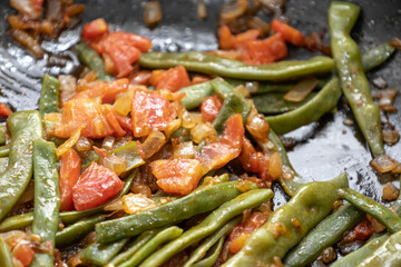 Fried green beans with tomato and onion pieces. Tasty meal with french bean on dinner or lunch on the pan