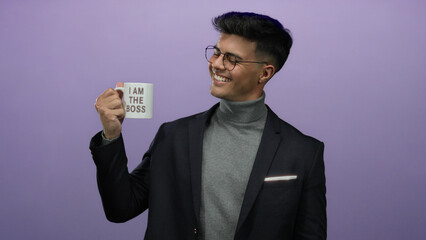 Young man with glasses smiling holding a mug with 'i am the boss' written on it against an isolated purple background