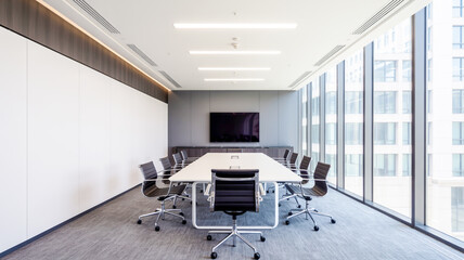 A modern, minimalist conference room with a white rectangular table in the center