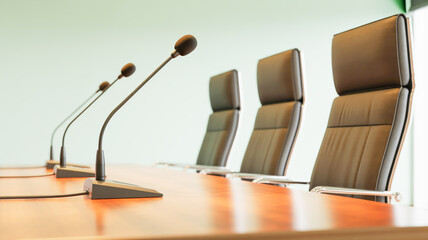 A professional conference room setup with three black gooseneck microphones mounted on a polished wooden desk