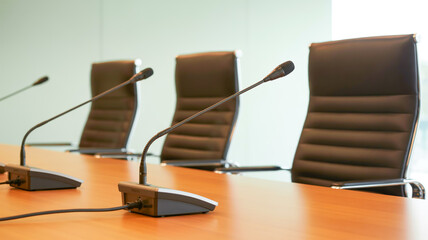 A professional conference room setup with three black gooseneck microphones mounted on a polished wooden desk