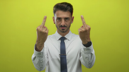 Man flips both middle fingers at camera in yellow studio wearing white shirt and tie; defiance...