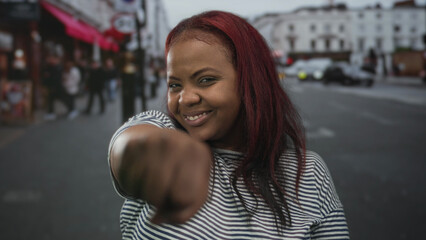 African american woman places fist to chest on busy street amid blurred buildings; solidarity...