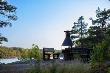Traditional Finnish grillipaikka in the forest with a metal grill or BBQ setup, a cozy place to...