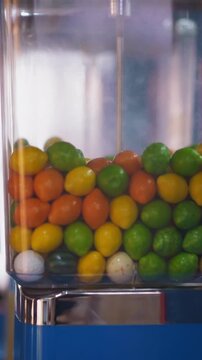 Gumball vending machine with plastic container full of candies installed on blurred background in hall of modern shopping mall closeup