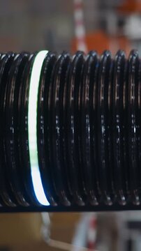 Dark corrugated plastic tube with glowing led rings changing colors as decorative element on blurred background in shopping mall super closeup