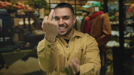 Man shows middle finger gesture in a clothing store building while wearing a yellow jacket;...