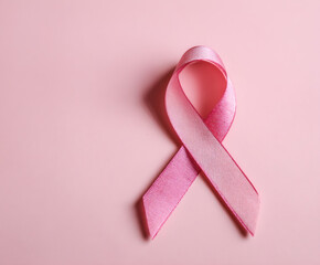 A pink ribbon of breast cancer awareness on a pink background.