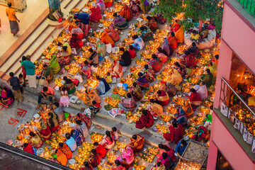 Dhaka, Bangladesh - 13 November 2018: Aerial view of a vibrant gathering, a sea of colorful saris and glowing candles creating a mesmerizing spectacle of light and tradition.