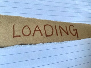 Word Loading written on brown background with two sheets of torn lined papers.
