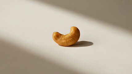 Single Cashew Nut Elegantly Displayed in Natural Light Casting Shadows on a Cream Colored Surface Creating an Appetizing Still Life
