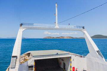 A unique perspective shot from a ferry's open bow ramp shows the vast, blue sea stretching toward...