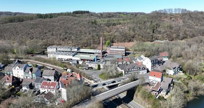 town nestled by the Wupper river, with a factory complex and a bridge crossing the water in Germany