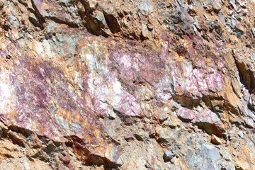 Close-up of rough, textured rock face with various shades of rust, brown, and gray