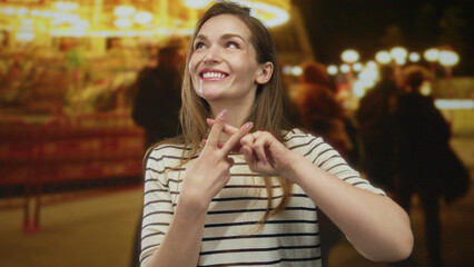Young caucasian woman forming hashtag gesture with interlocked fingers on illuminated street at night; social connection.