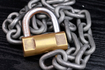 Padlock and chain on dark background.