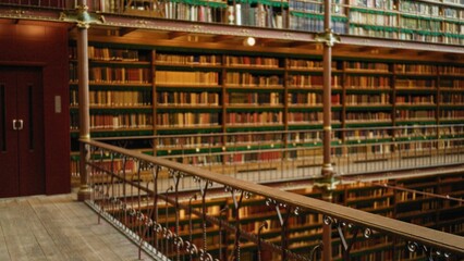 Blurred view of a historic library with bookshelves filled with old books, showcasing a defocused interior with rich woodwork and classic railings. © Krakenimages.com