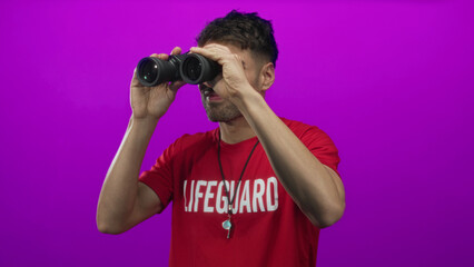 Young hispanic lifeguard holds binoculars to eyes while wearing a whistle necklace in purple...