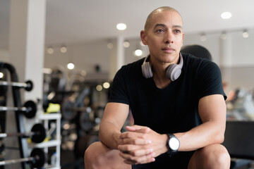 Hispanic bald man athlete in gym sitting ready for workout