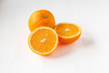 Halved orange fruit on white wooden background