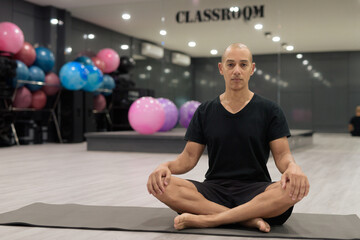 Hispanic bald man athlete in gym classroom doing yoga meditation while sitting