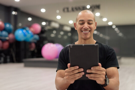 Hispanic bald man athlete in gym classroom using digital tablet computer - Powered by Adobe