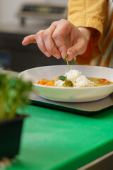Professional Chef Garnishing Vibrant Thai Yellow Curry with Basil on Basmati Rice in Kitchen, Side View
