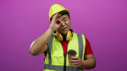 Young man wearing safety gear including hard hat and reflective vest gesturing okay sign while...