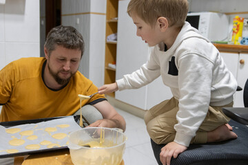 Father and son baking cookies together in kitchen
