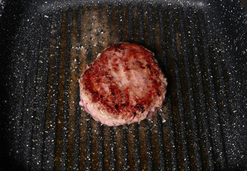 Juicy burger patty grilling on a hot pan
